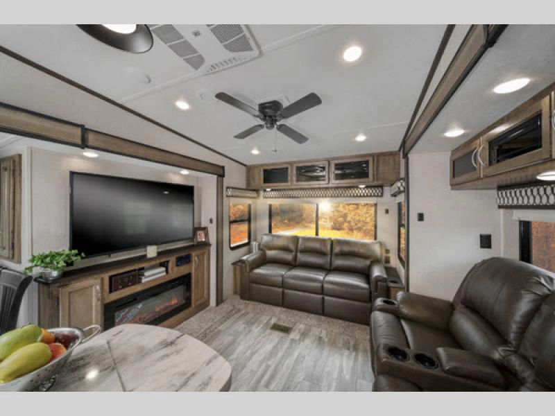 RV living room area with sofa, recliners, TV, and fireplace