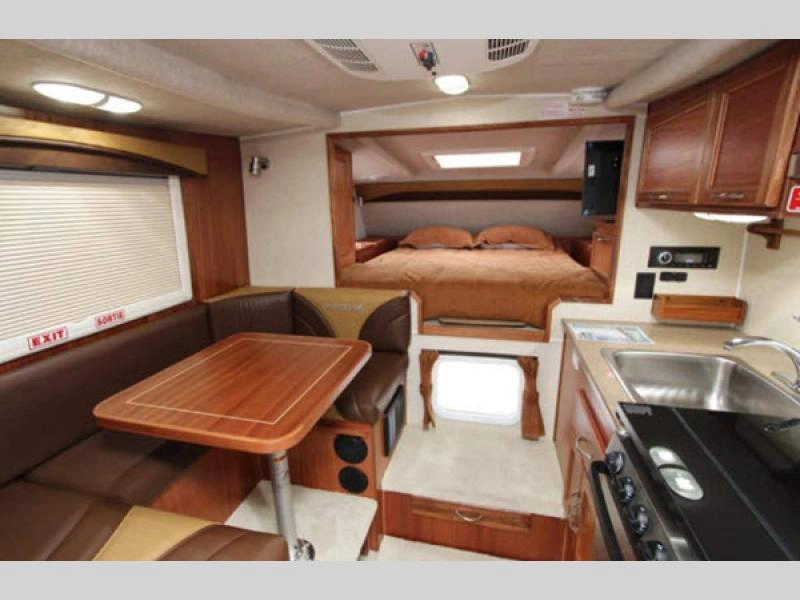Northern Lite truck camper interior with queen bed, convertible dinette, and kitchen