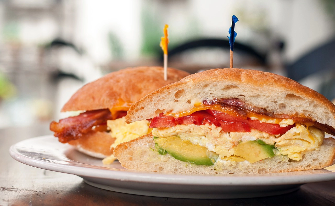 Easy breakfast sandwich with egg, meat, vegetables, sliced on a plate