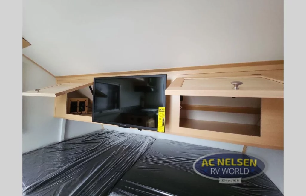 Ascape Travel Trailer- sleeping area with flat-screen TV, and storage cabinets