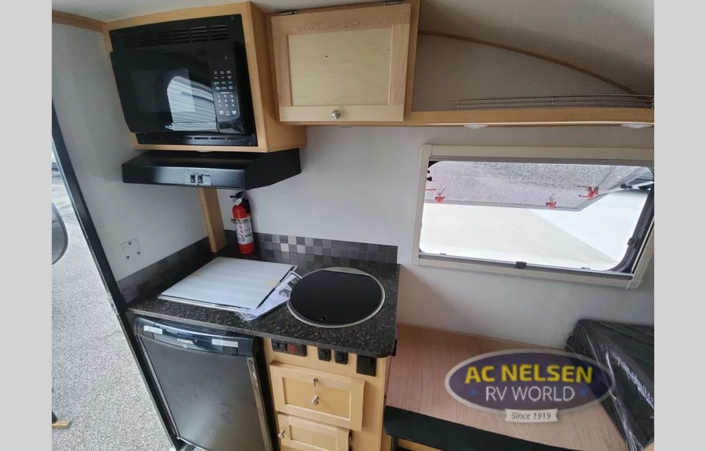 Ascape Travel Trailer- interior kitchen with refrigerator, stove, sink, microwave, fan, cabinets